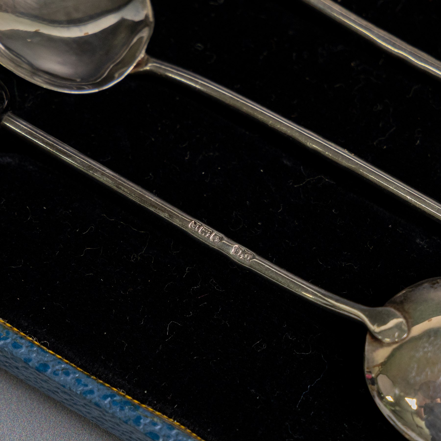 Two sets of early 20th century cased silver coffee spoons, comprising a set of six with scrolling decoration and engraved initials and a set of six coffee bean spoons, all hallmarked 