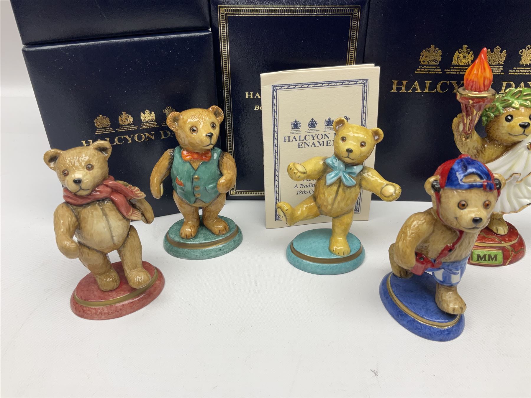 Eight Halcyon Days Teddy Bear of the Year figures, from 1993 to 2000, including one example modelled as a bear in Greek dress carrying a torch, one example modelled as a schoolboy and one example in a blue dress, all boxed 
