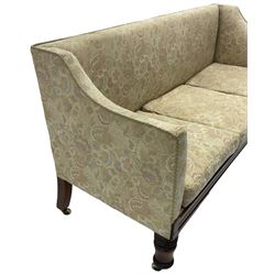 Victorian mahogany framed three-seat settee, upholstered in floral pattern fabric, on turned feet with brass and ceramic castors 