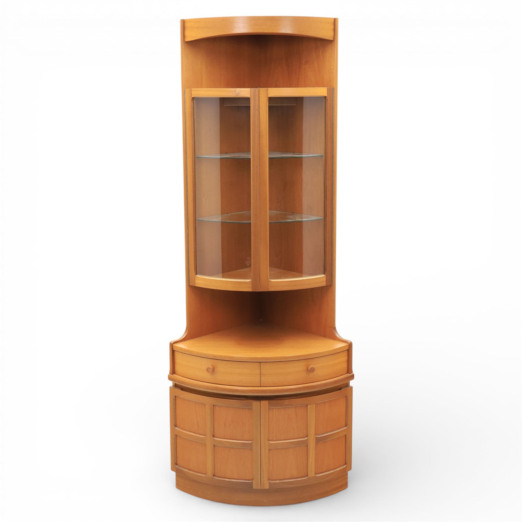 Nathan - 'Squares' corner cabinet, the upper section enclosed by two curved glazed doors with glass shelves, over a shaped base fitted with a single frieze drawer and panelled twin cupboard doors