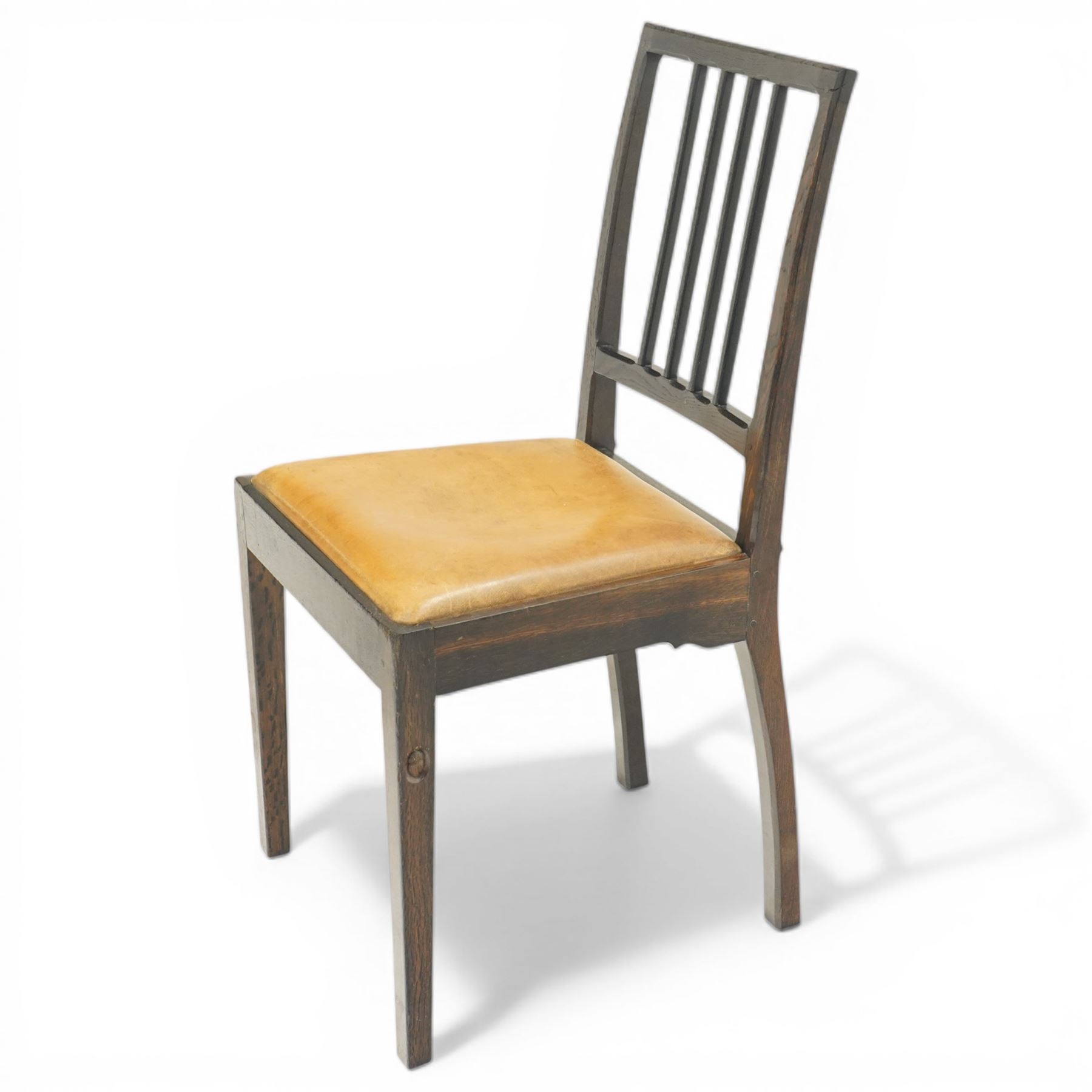 Acornman - set of four dark stained oak dining chairs, with four vertical slats, drop-in tan leather seat, supported on square tapering legs with carved acorn signature, by the workshop of Alan Grainger of Brandsby