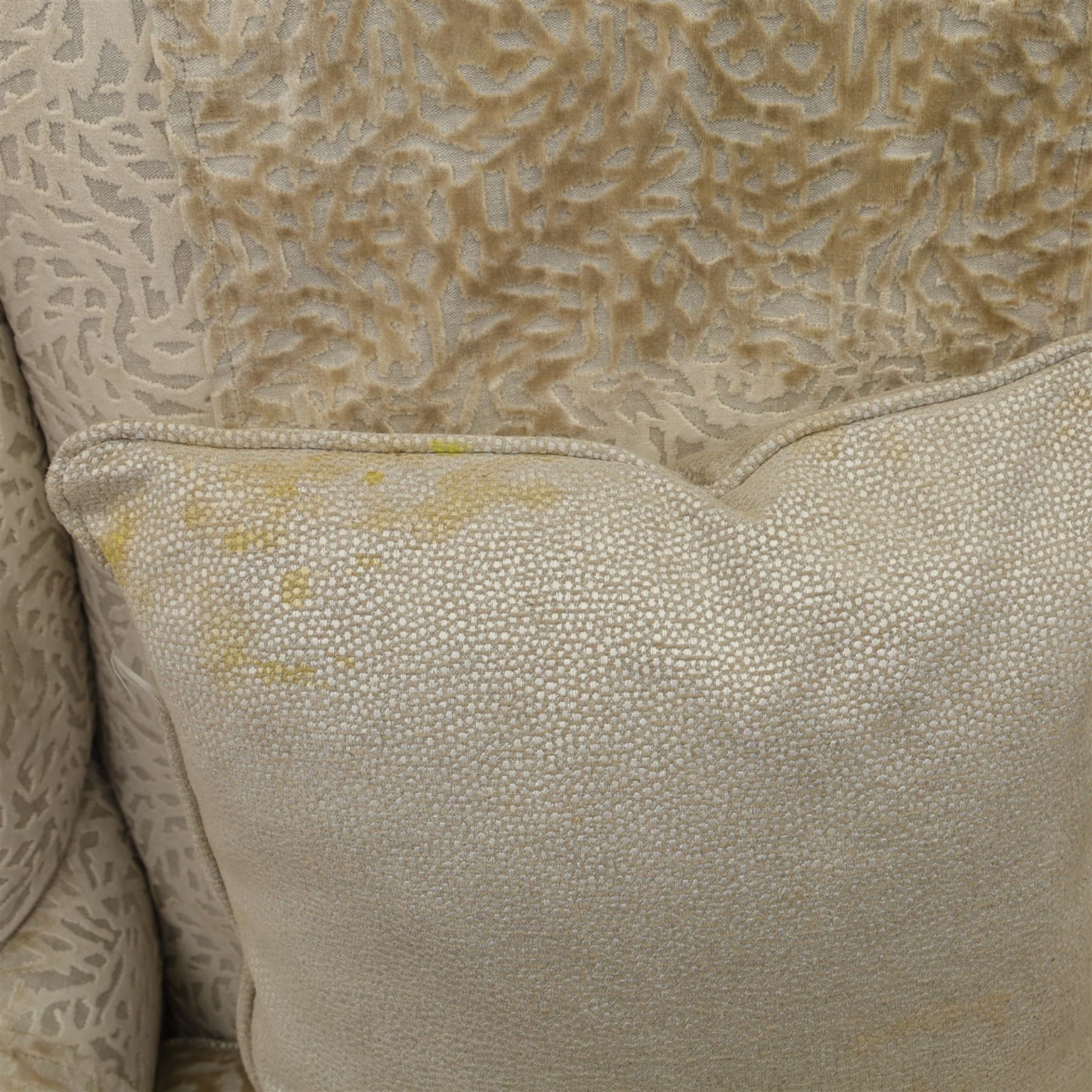 Late 20th century wingback armchair and matching footstool, upholstered in beige embossed fabric with brass stud edging, on cabriole legs and splayed rear legs, together with a matching footstool on turned supports terminating in brass castors (Stool H 42cm, W 75cm, D 47cm)