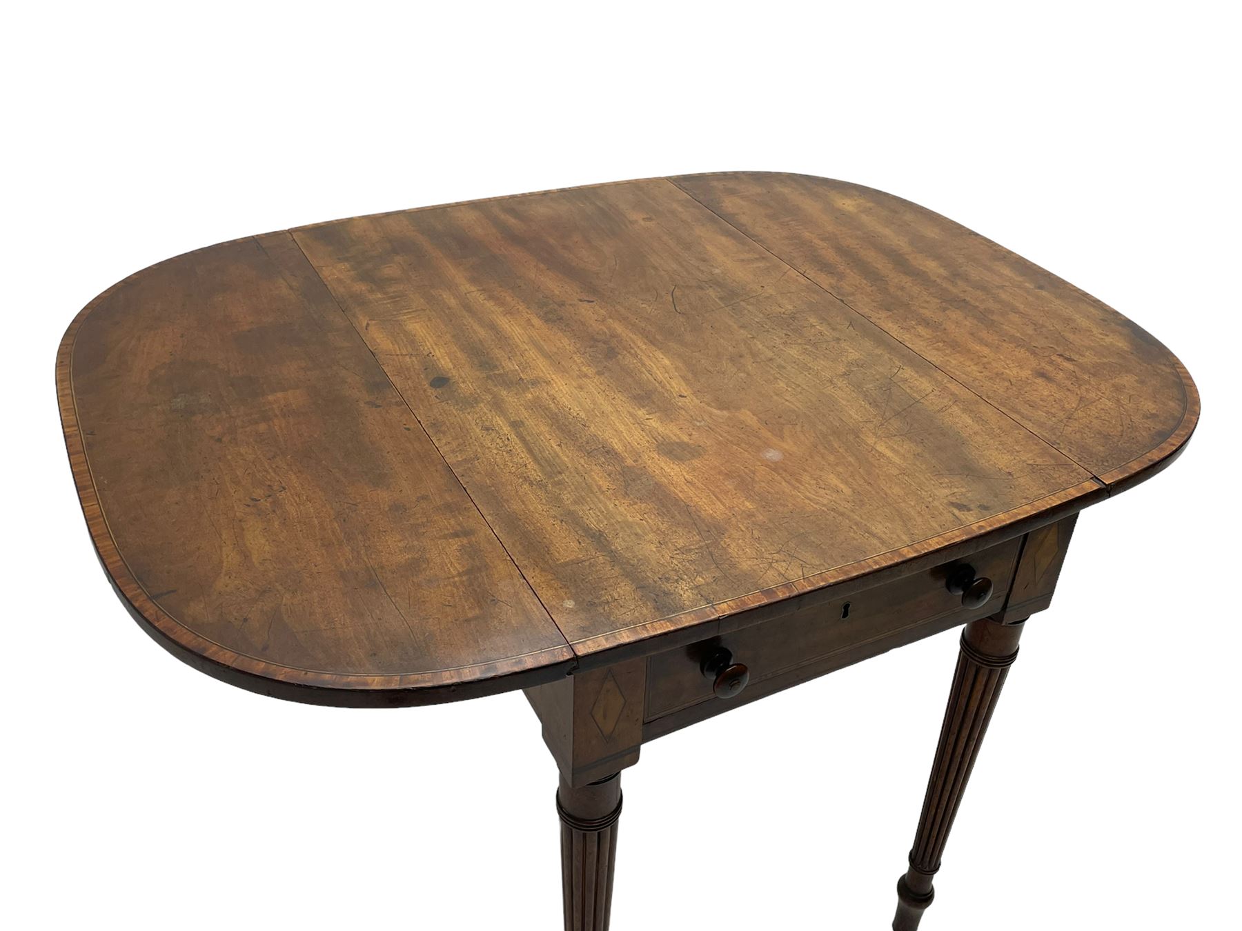 George III mahogany Pembroke table, drop-leaf oval top with satinwood band, fitted with single end drawer, inlaid with satinwood lozenge motifs, on turned and reeded supports with brass cups and castors