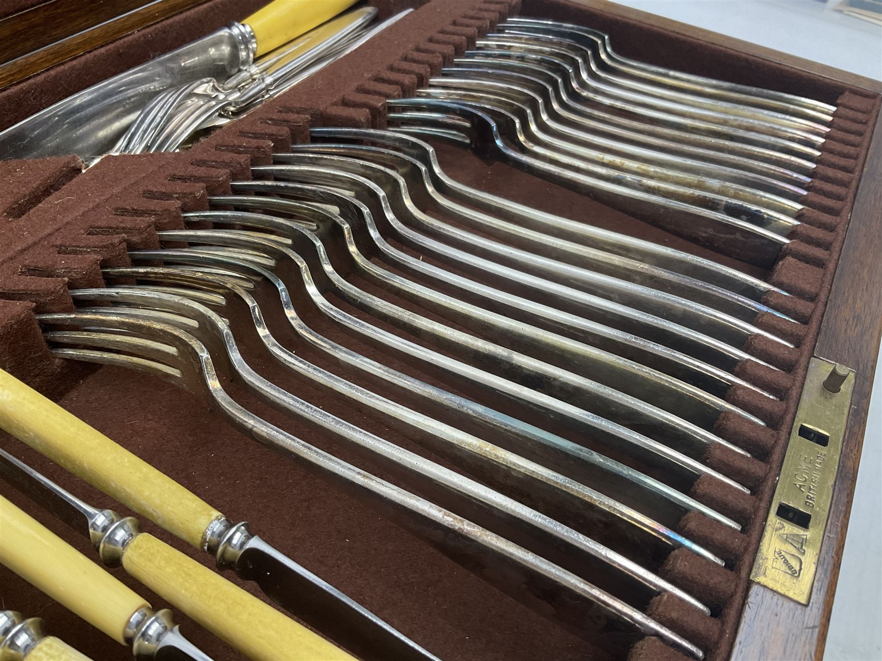 Elkington & Co part canteen of silver plated and stainless steel cutlery, to include simulated ivory handled examples, housed in oak and mahogany case, lock plate stamped 'Acme, British Made', W49cm D31cm H18cm