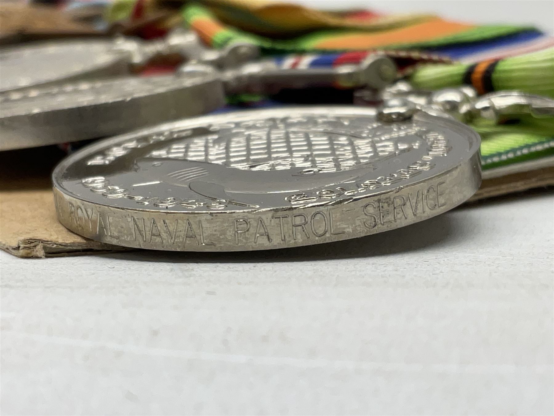 WW2 Royal Naval group of eight medals comprising OBE, hallmarked silver Distinguished Service Cross inscribed verso Lieut. J.R. McCluskie RNVR 1945, 1939-1945 Star, Atlantic Star, Africa Star, 1939-1945 War Medal, Defence Medal and Royal Naval Patrol Service Medal inscribed Lieutenant J.R. McCluskie Royal Naval Patrol Service; with seven original photographs of a sea battle 27th November 1940 against the Italian Fleet and another photographic postcard of Sir Stafford Cripps arriving on board one of the vessels.