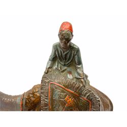 After Franz Bergmann, a cold painted spelter table lighter modelled as a figure upon a camel table with two rug traders, raised on faceted black glass base, H19.5cm 