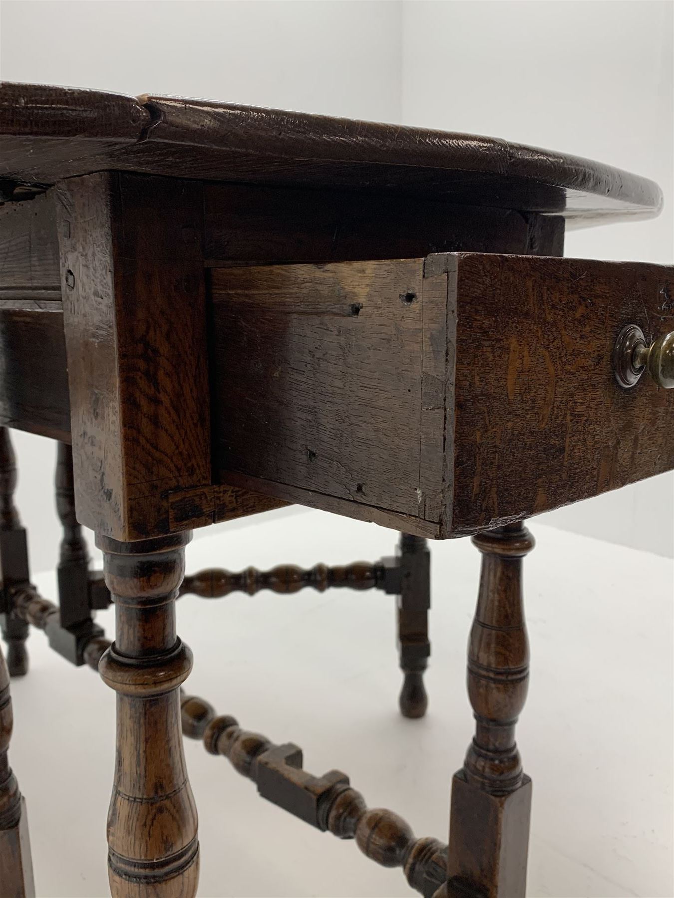 Late 17th century William & Mary oak drop leaf dining table, oval drop leaf top, single drawer to one end, gate action base, turned supports joined by bobbin turned stretchers, 121cm x 135cm, H75cm (open)