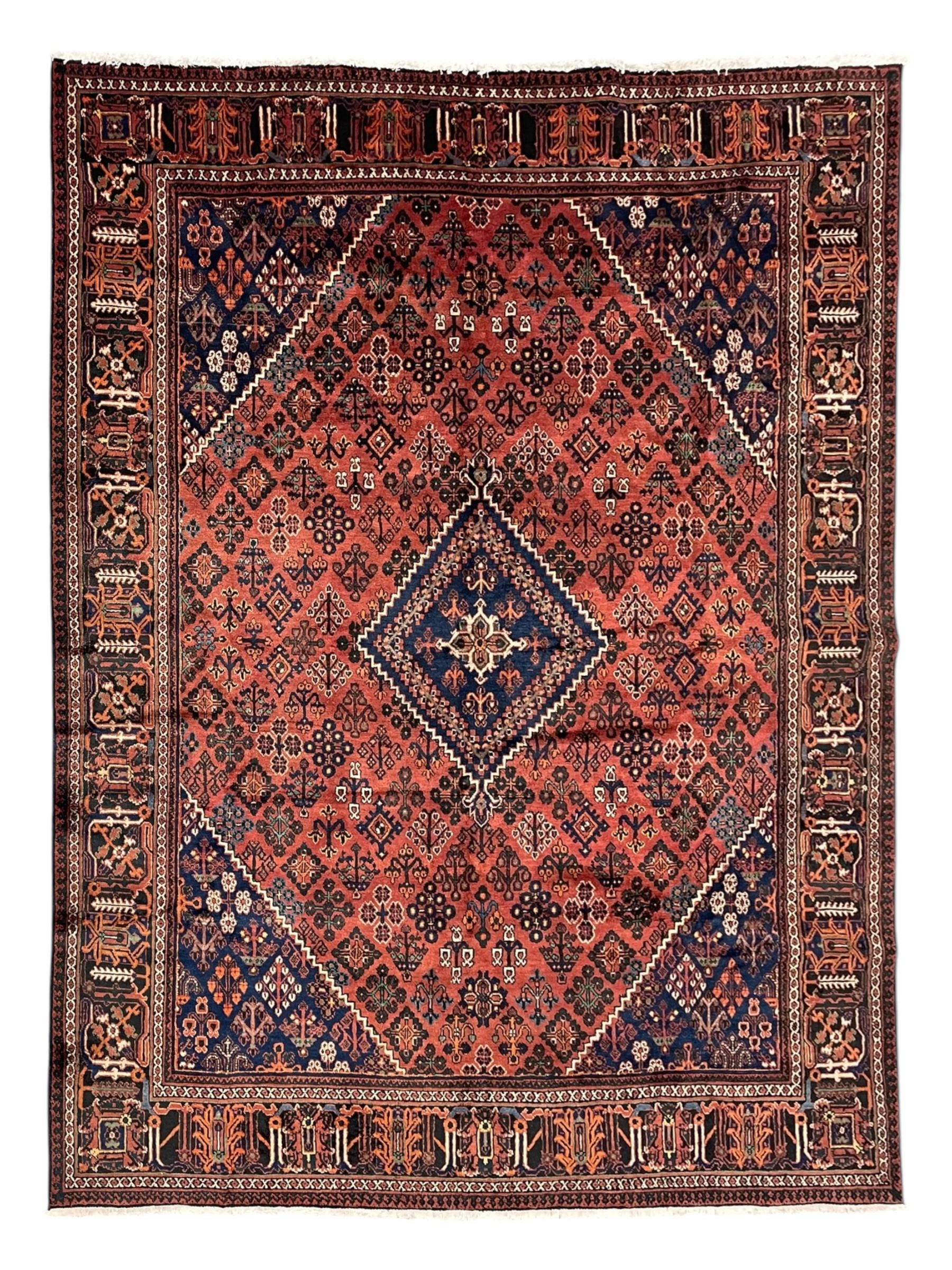 Persian Joshaghan red ground rug, stepped lozenge medallion surrounded by small lozenge motifs, the border decorated with stylised plant motifs within patterned guard stripes