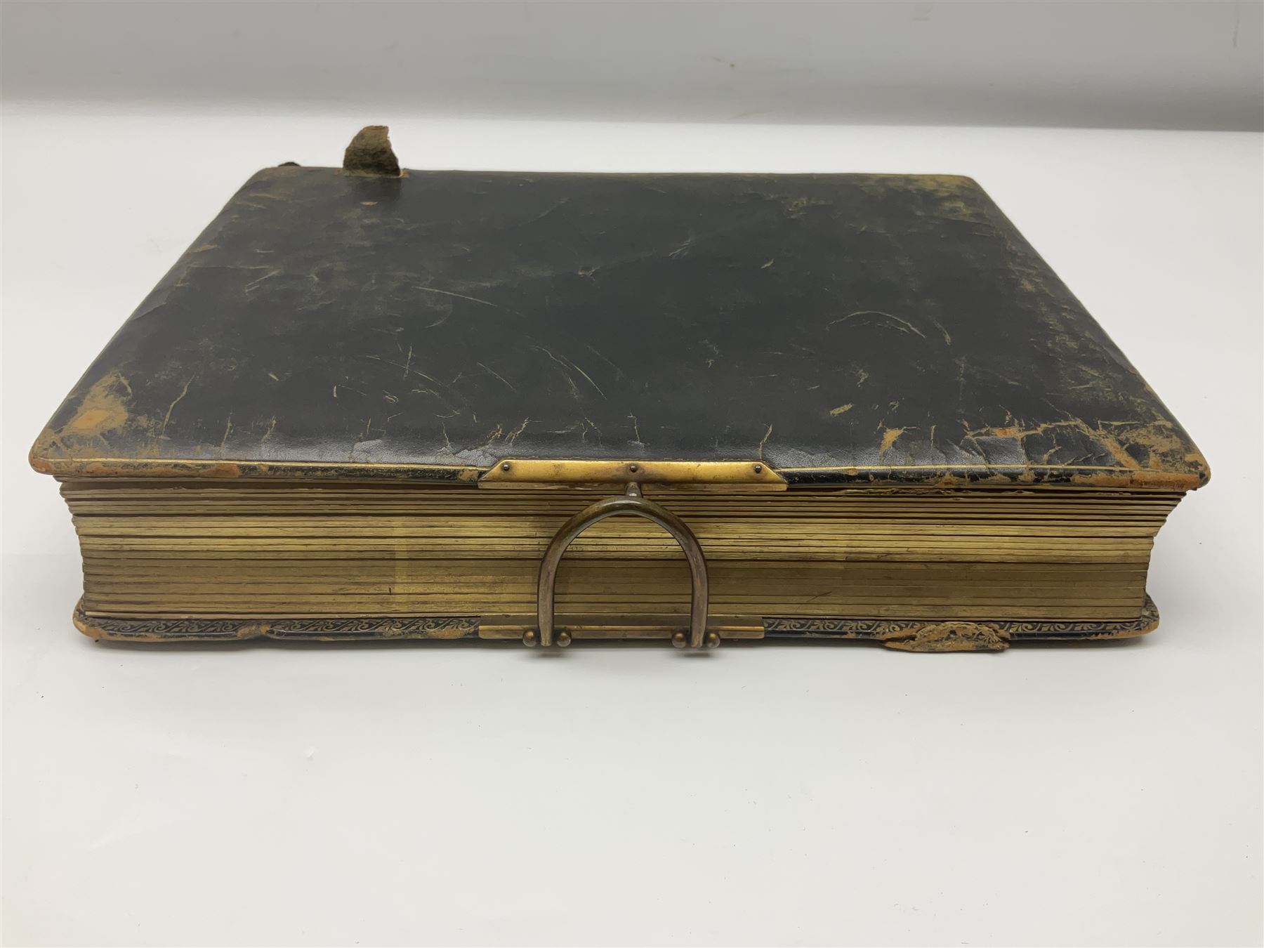  Victorian leather bound photo album, the interior leaves containing apertures of various sizes and shapes of portraits surrounded by printed floral designs, with brass clasp and painted gold decoration to edges, H30cm
