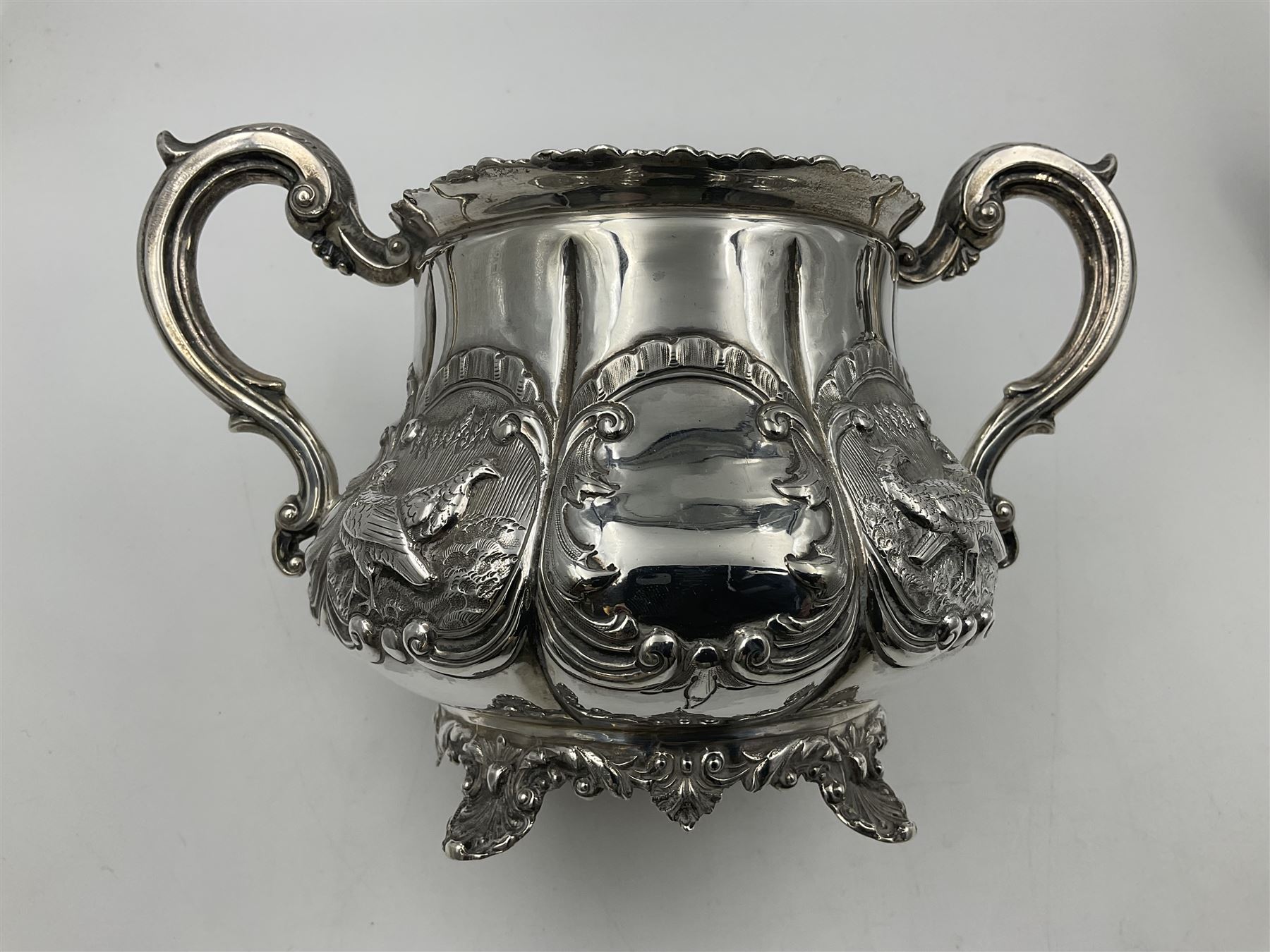 Victorian silver three piece tea service, comprising teapot, twin handled open sucrier, and milk jug, each of bellied form with acanthus capped scroll handles, the sides embossed with alternating scroll edged vacant panels and panels containing a pair of birds, upon four palmette feet, the teapot with ivory insulators to handle, and bird finial to the hinged domed cover, hallmarked William Hunter & Son, London 1861, teapot H19cm, including handles sucrier H13.5cm, including handle milk jug H12cm

This item has been registered for sale under Section 10 of the APHA Ivory Act