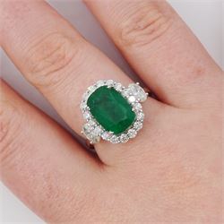 18ct white gold emerald and diamond cluster ring, single cushion cut emerald of approx 2.45 carat, surrounded by eighteen round brilliant cut diamonds, with a single oval cut diamond set either side, stamped, total diamond weight approx 1.05 carat