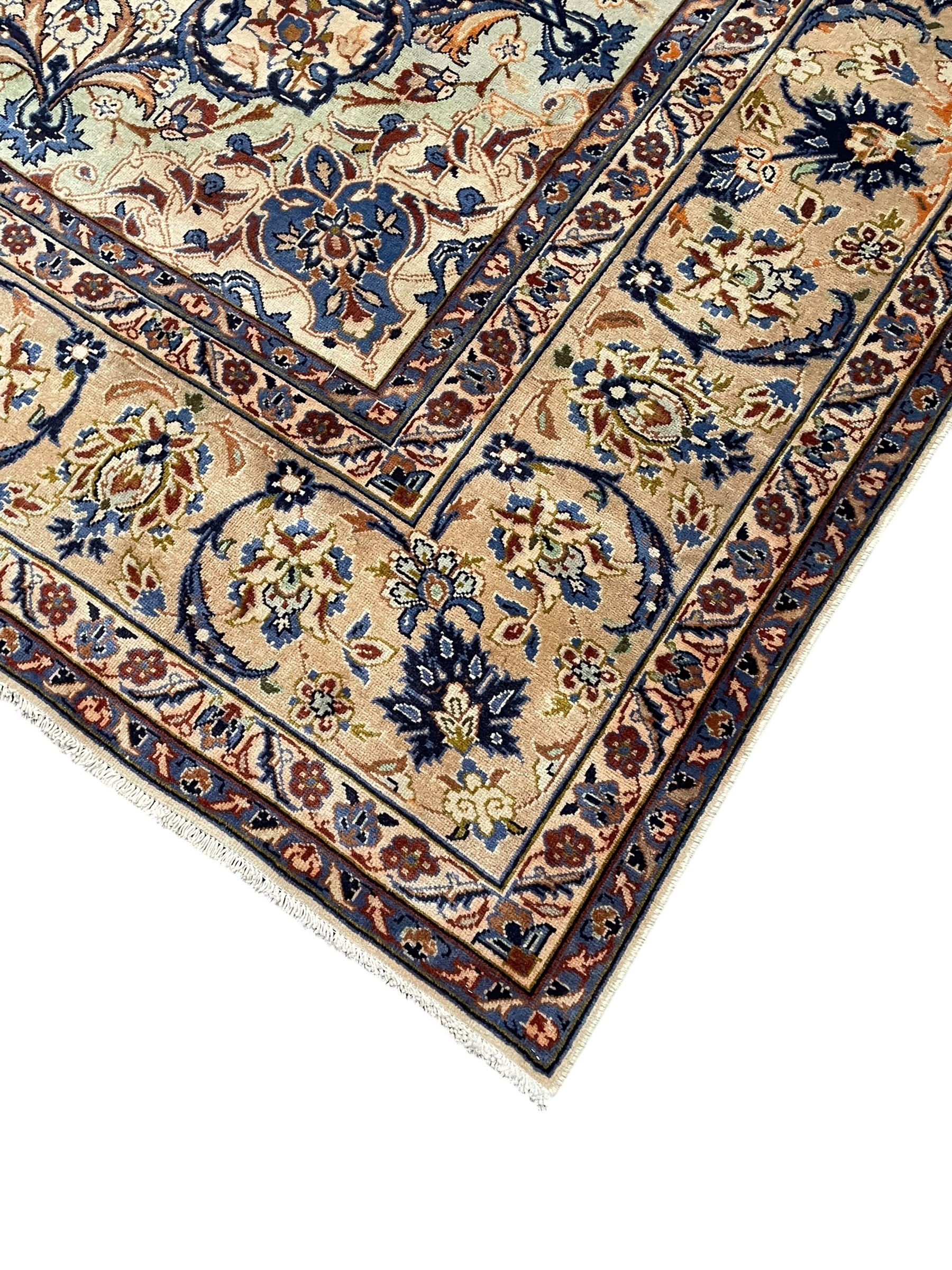Persian Kashan ivory ground carpet, floral design central medallion surrounded by trailing and interlaced leafy branches with palmettes and flower heads, matching patterned border with guard stripes 