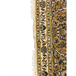 Persian Kashan ivory ground carpet, the field decorated with trailing foliate branches and stylised flower head motifs, guarded border with repeating design decorated with scrolling leafy branch and plant motifs 
