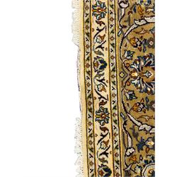 Persian Kashan ivory ground carpet, the field decorated with trailing foliate branches and stylised flower head motifs, guarded border with repeating design decorated with scrolling leafy branch and plant motifs 