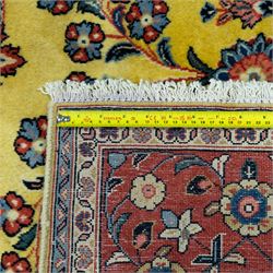 Persian Sarough hand-knotted carpet, golden yellow ground, with an all-over floral design centred by a small floral motif, the field decorated with mirrored flowering sprays, scrolling vines and dark navy foliate corner motifs, enclosed by a terracotta border with repeating flowerheads and palmettes, flanked by narrow guard stripes, with cotton fringes