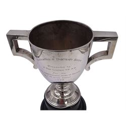 1920s silver trophy cup, with angular twin handles, upon knopped stem with circular spreading foot, the body with presentation engraving 'Burniston & District Show, presented by S Fox Linton TD MD, for the Best Agricultural Mare or Gelding, 10 miles radius, 1928' and engraved with winners verso, hallmarked Charles Boyton & Son 1921, upon black plastic base, including base 25cm