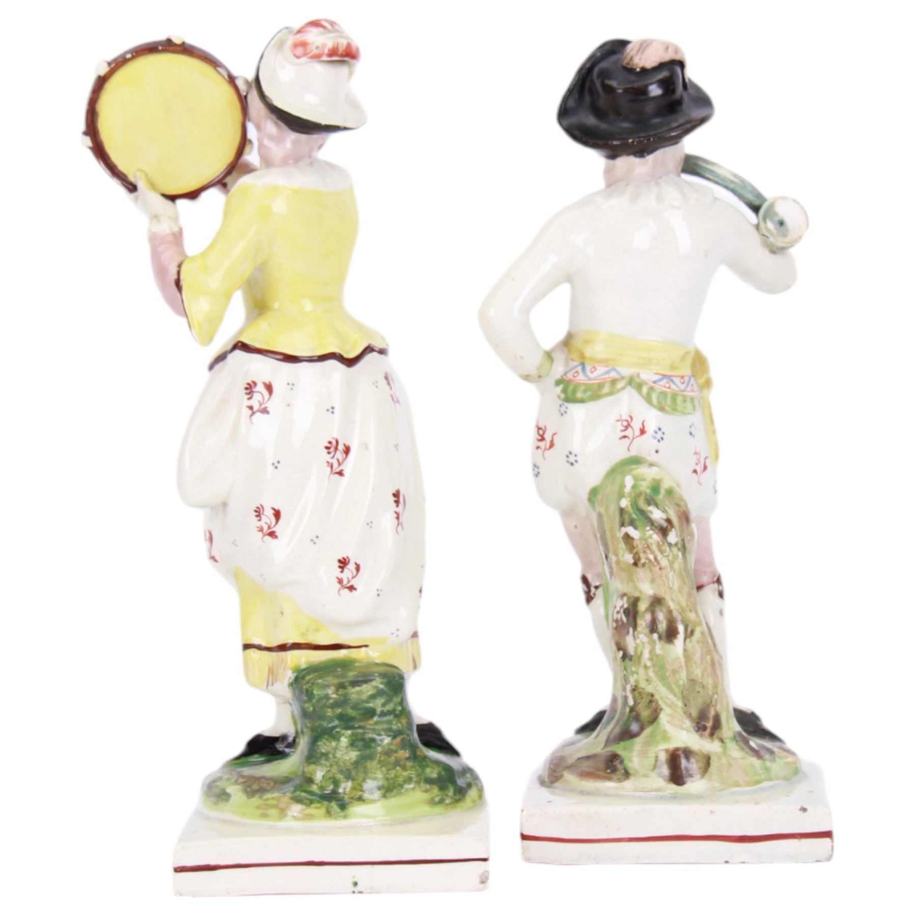 Pair of early 19th century Staffordshire pearlware figures, modelled as musicians, he playing the French horn, she the tambourine, each upon square plinth, tallest example H23cm