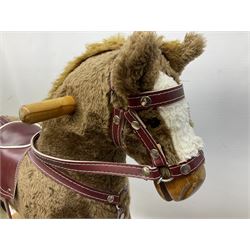 Modern plush covered rocking horse with inset eyes, simulated leather bridle and saddle with metal stirrups, on curving wooden rockers L94cm H64cm