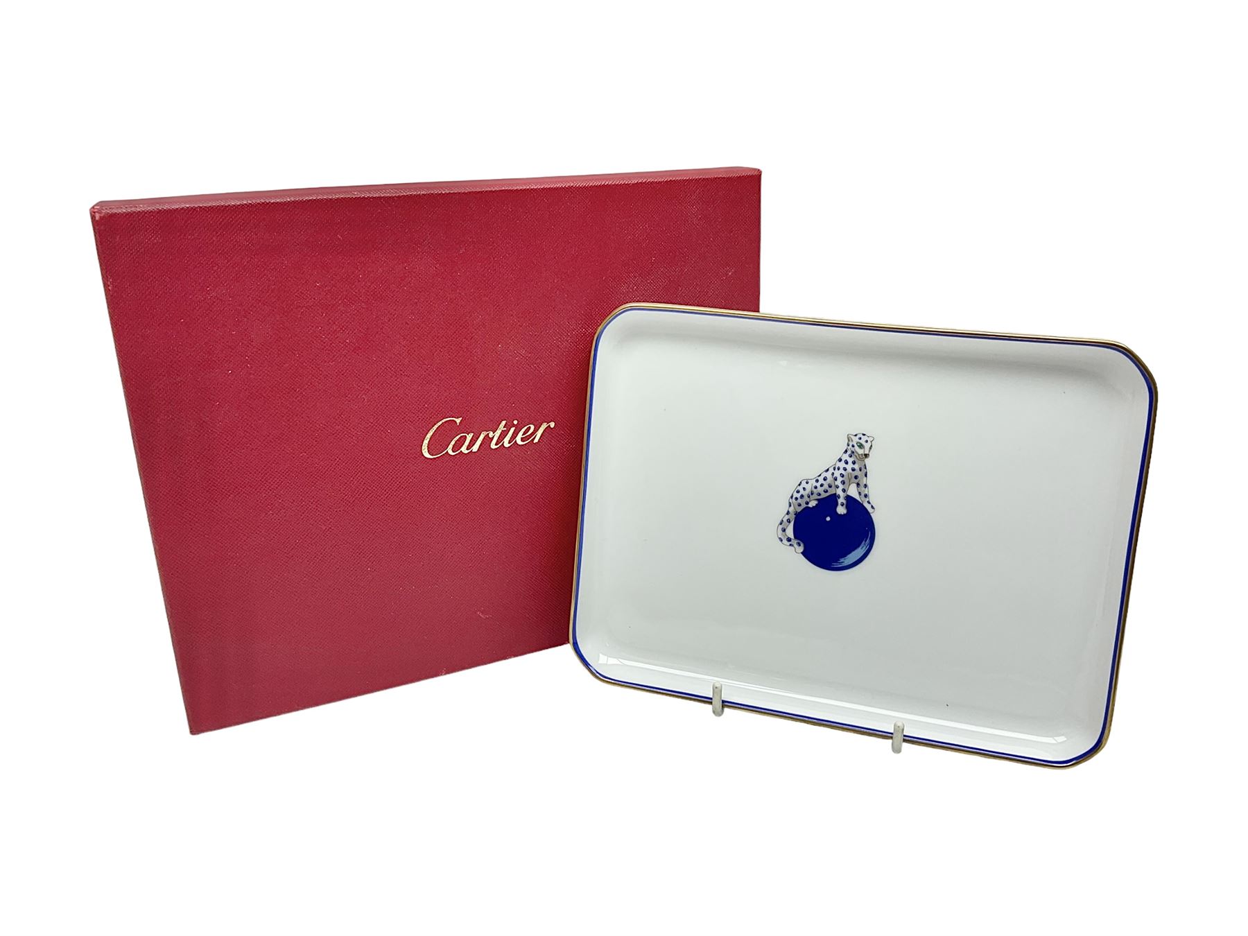 Limoges for Cartier, ceramic trinket dish, of rectangular form with rounded corners, decorated to centre with leopard upon a blue ball, with blue and gilt rim, with printed mark beneath, in original box, H15.5cm, W21cm