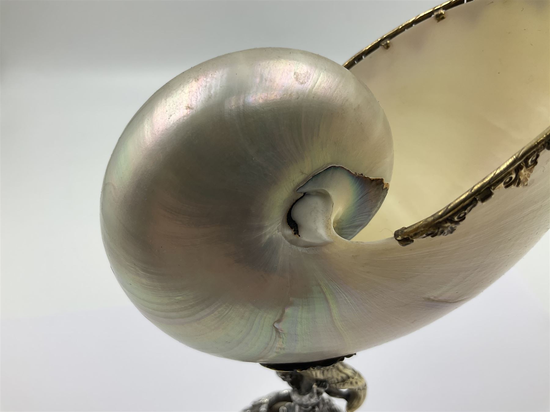 Modern limited edition silver mounted nautilus shell cup, no. 42/150, the pearlescent shell cup with silver-gilt strapwork to rim, upon a stem modelled as a putto supporting a gilt cornucopia and circular domed foot depicting Poseidon amongst swirling waves, hallmarked by St James House Company, London 1980,  H17.5cm