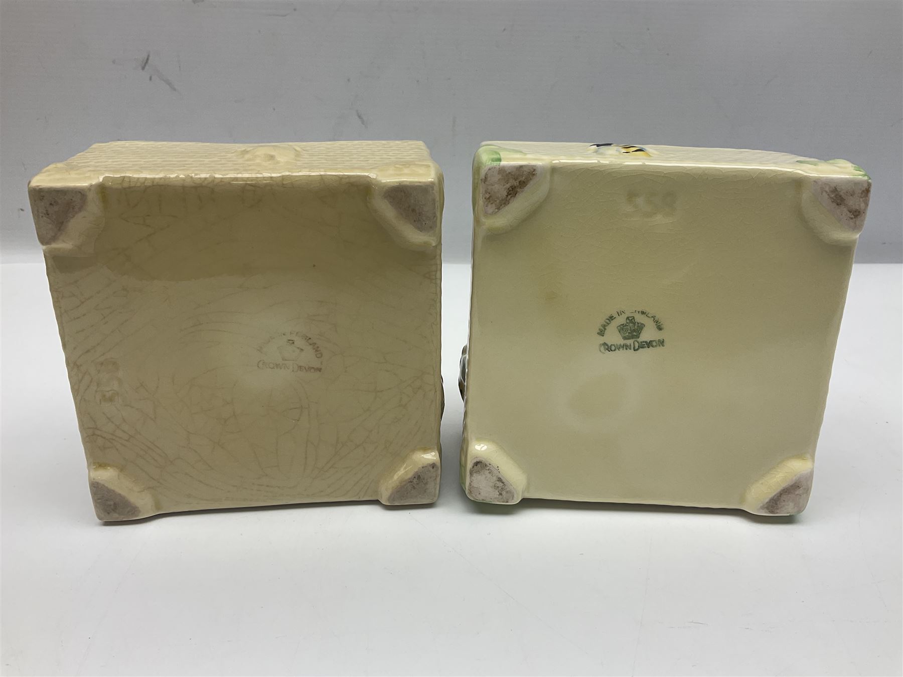 Four square honey boxes with lids,  each decorated with honeycomb pattern and finished with a bee finial