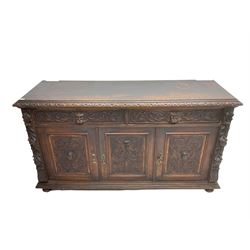 Victorian heavily carved oak sideboard, the moulded top carved with foliate decoration to the edge, fitted with two drawers and three cupboards, the drawer fronts carved with green man mask handles and scrolling foliage, the panelled doors carved with interlacing foliage, on turned compressed bun feet