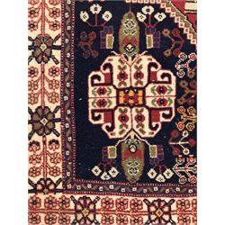 Fine Persian Qashqai crimson and navy ground runner, three large medallions filled with geometric and floral designs, the field with angular vines and stylised floral decoration, wide ivory border decorated with repeating floral and angular motifs