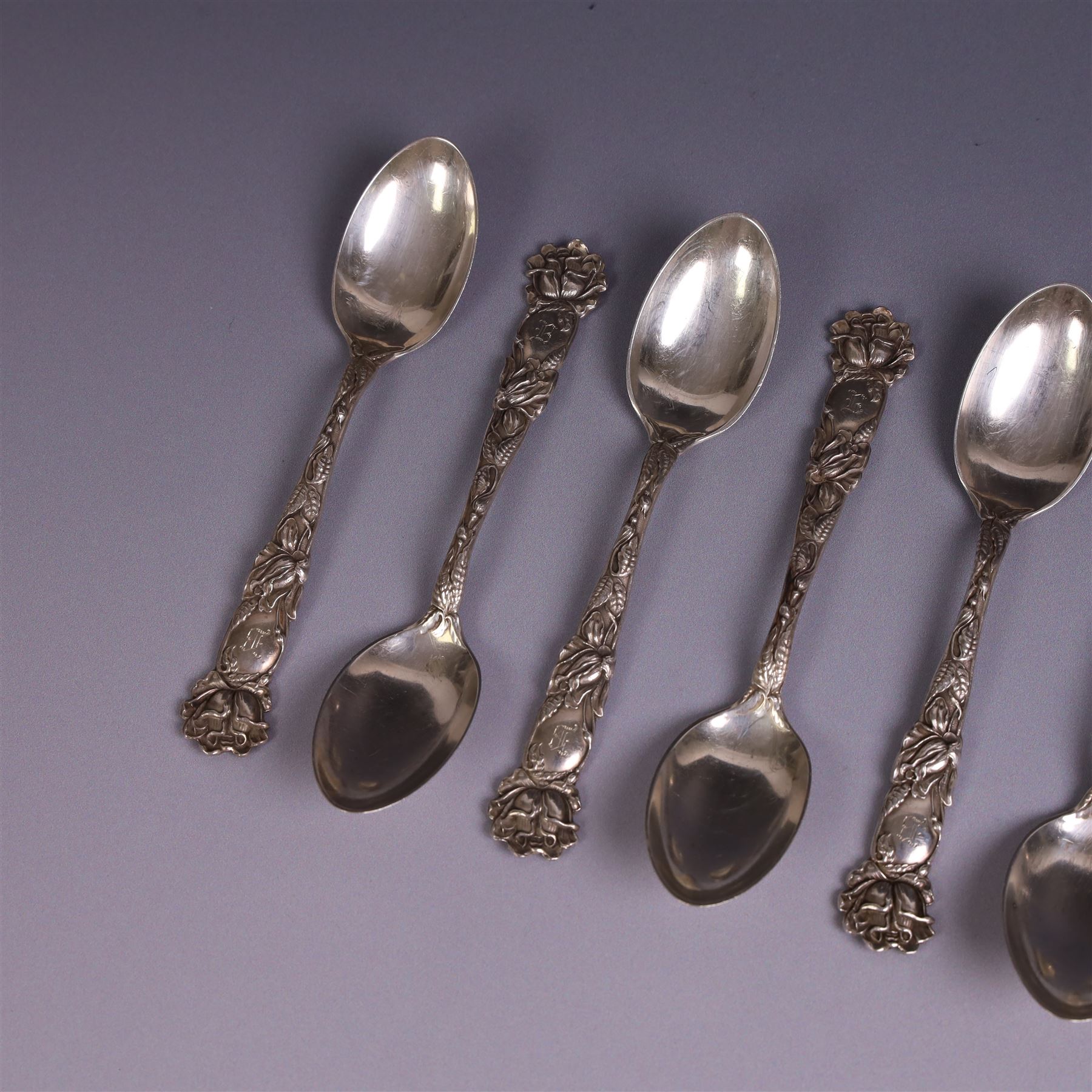 American silver tea and coffee spoons, comprising set of six coffee spoons with embossed lily decoration, set of six teaspoons with embossed rose decoration, both with engraved initials and a pair of Larkin coffee spoons, all stamped Sterling