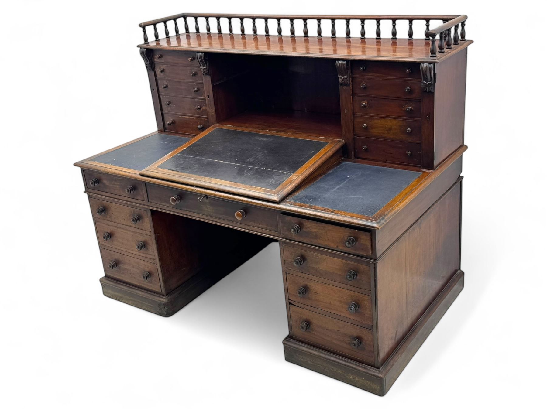 Large Victorian mahogany Registry/Dickens’ desk, spindle gallery top, one side with five small drawers and the other with blind cupboard drawer, revealing pigeon holes with scroll carved locking side bars on either side, above a hinged and leathered writing slope with three drawers and pigeon holes underneath, above a central locking drawer with key, the pedestals each with four drawers and  turned knob handles, separates into four parts for transport