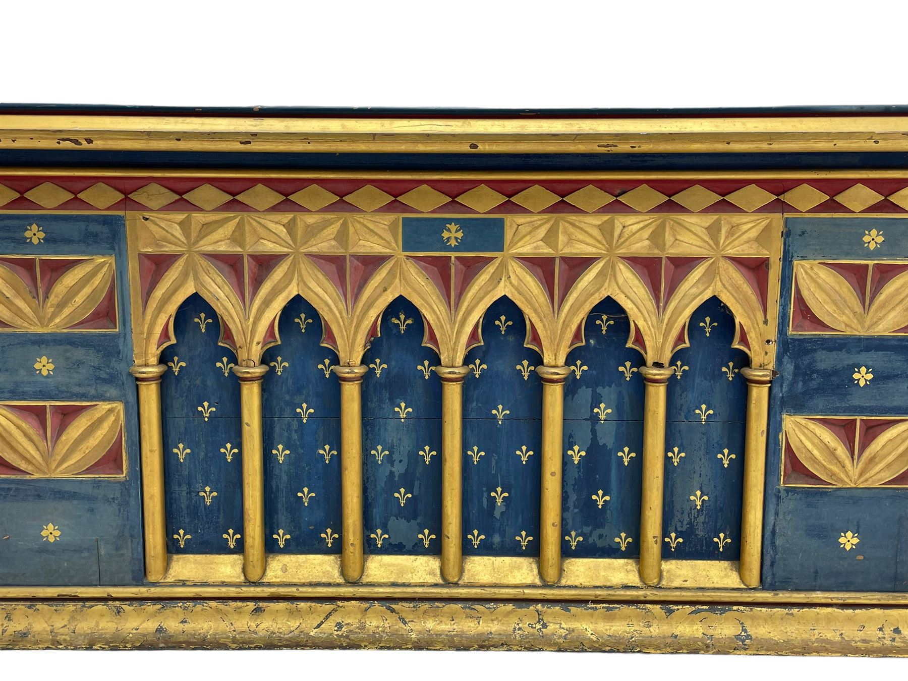 In the manner of William Burges - mid-to-late 19th century English Gothic Revival pine altar or console table, in blue and red paint with water gilding, the moulded rectangular top over six pointed arches with turned column supports, the front carved with a single row of lozenges and incised stylised motifs