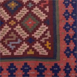 South West Persian Qashgai flatweave kilim, field decorated with a repeating diagonal lattice of stepped lozenges and angular hooked motifs, interspersed with small tribal devices, woven is shade of madder red, soft pink, indigo blue, ochre, and olive green, framed by a narrow geometric border and contrasting guard stripes 