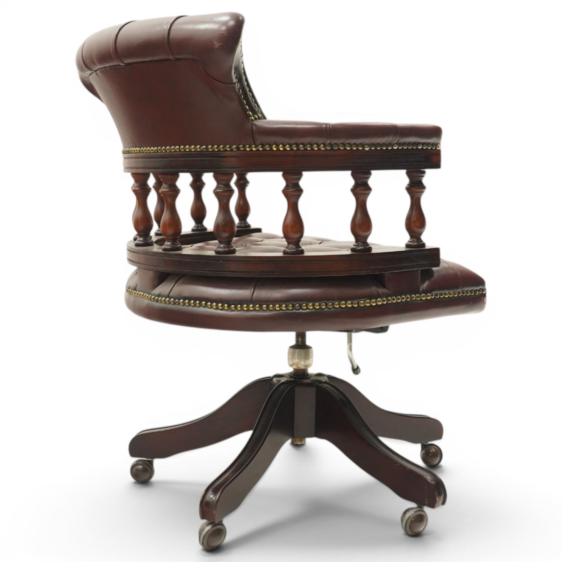 Georgian design captains swivel desk chair, rolled cresting rail over open spindle back on tripod base, upholstered in buttoned oxblood leather