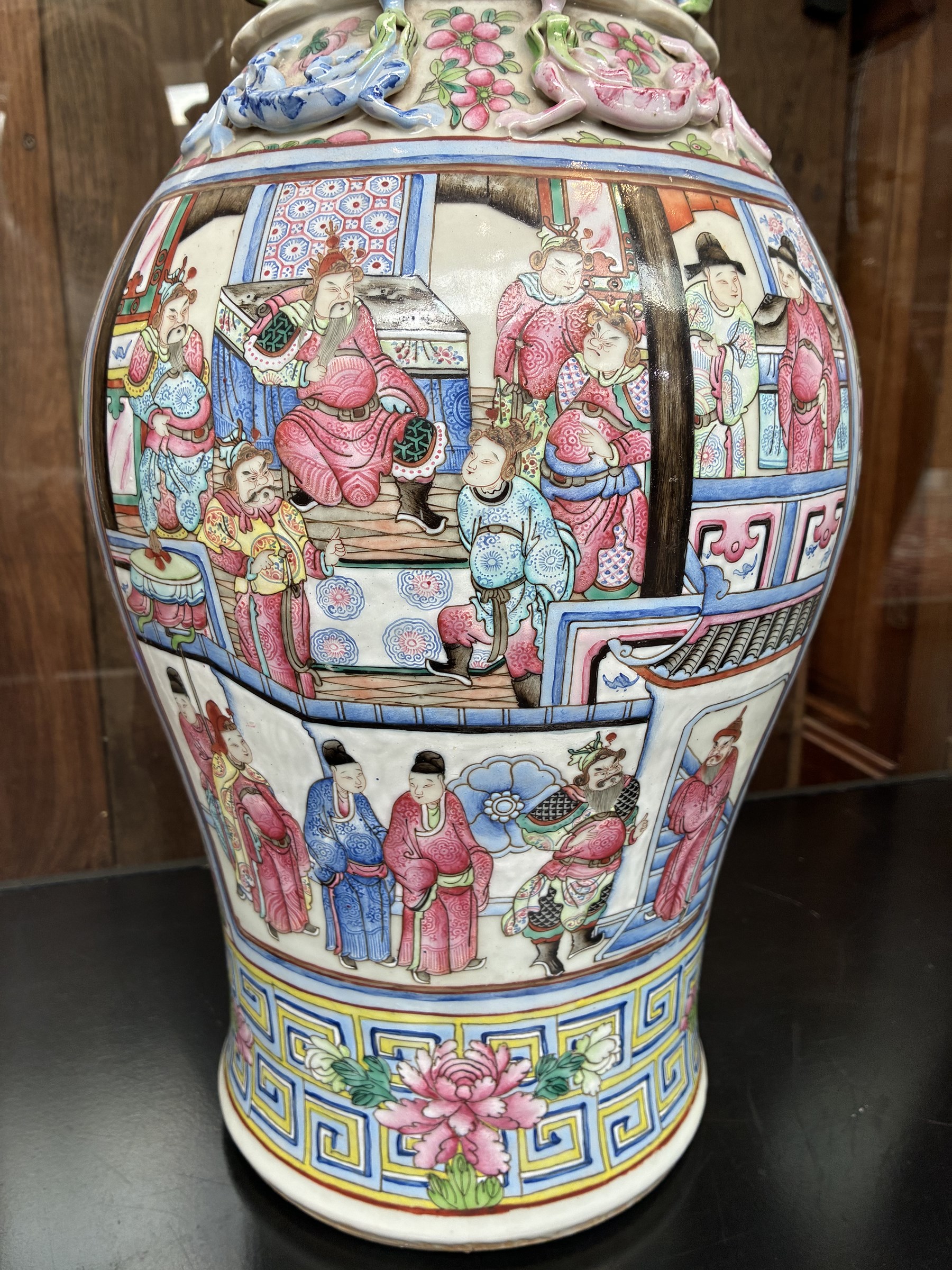 Large pair of 19th century Cantonese famille rose vases, each painted with various courtly scenes, including a display of warriors fighting on horseback before an official and his attendants, double Buddhist lion handles and applied at the shoulders with chilong, the lower band painted with Greek key motif, H58cm (2)