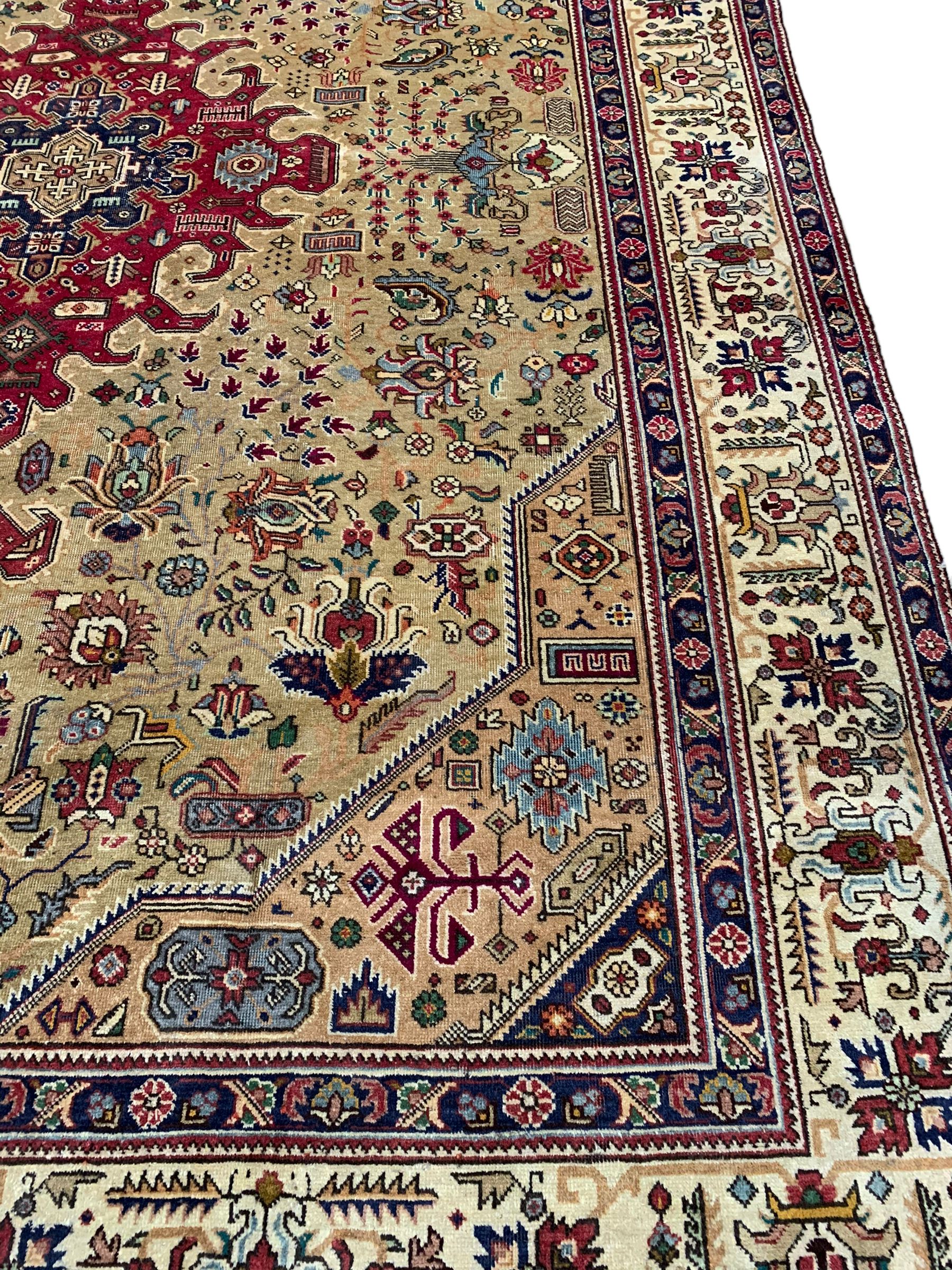 Persian Azarbaijan golden ground carpet, the shaped crimson ground medallion decorated with geometric motifs, the field profusely decorated with stylised plant and flower head motifs, repeating border with guard bands 