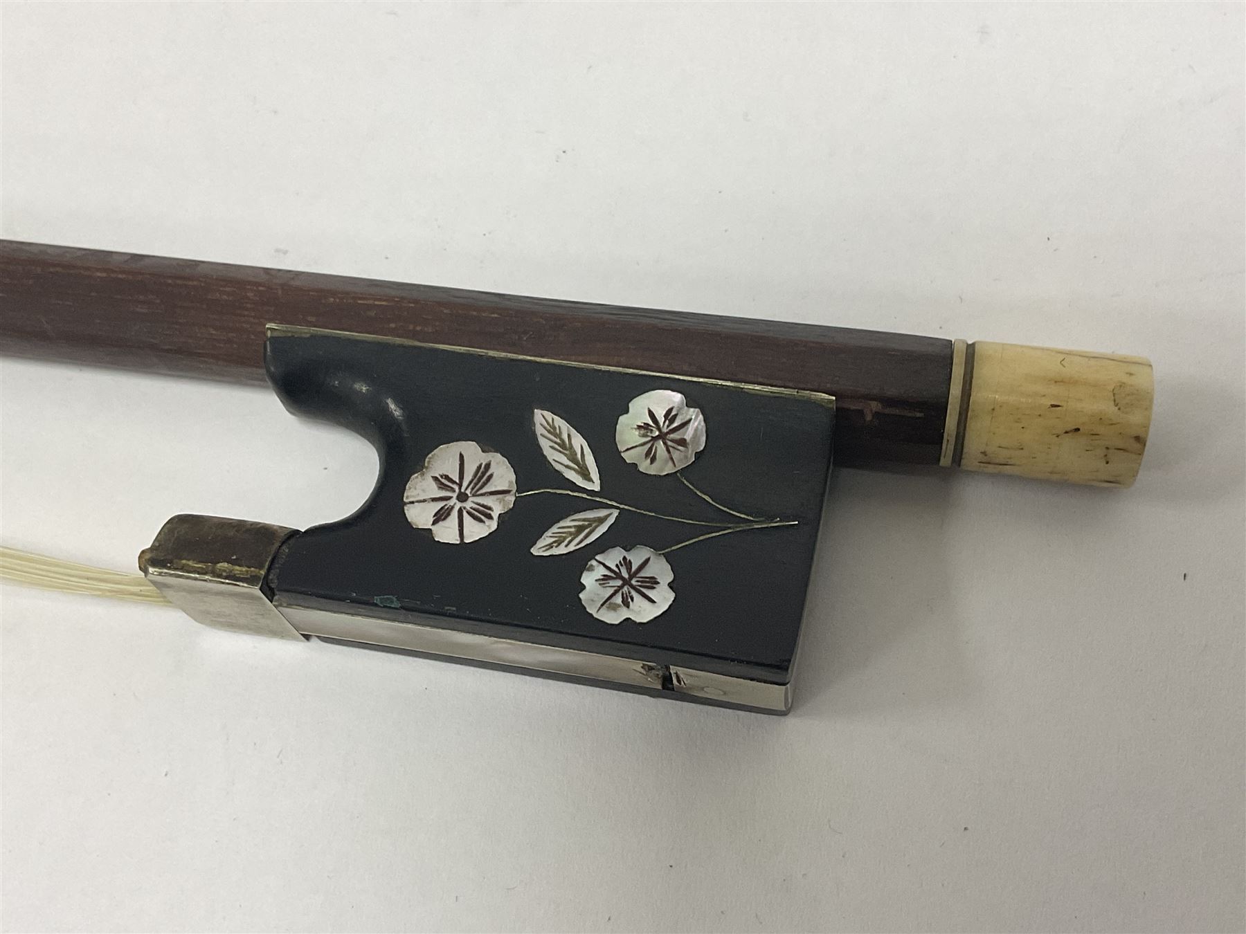 19th century wooden violin bow with a decorative mother of pearl inlay depicting flowers to the frog, with a bone adjuster screw