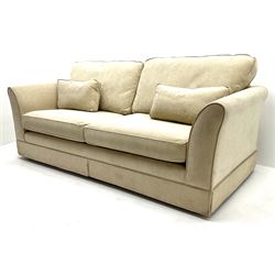 Large three seat sofa upholstered in cream fabric, castors 