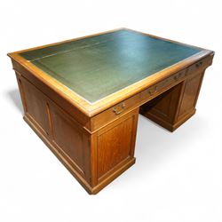Late 19th century twin pedestal oak partner's desk, rectangular top with inset green leather writing surface, fitted with nine graduating drawers to each side, the rear drawers enclosed by panelled cupboards