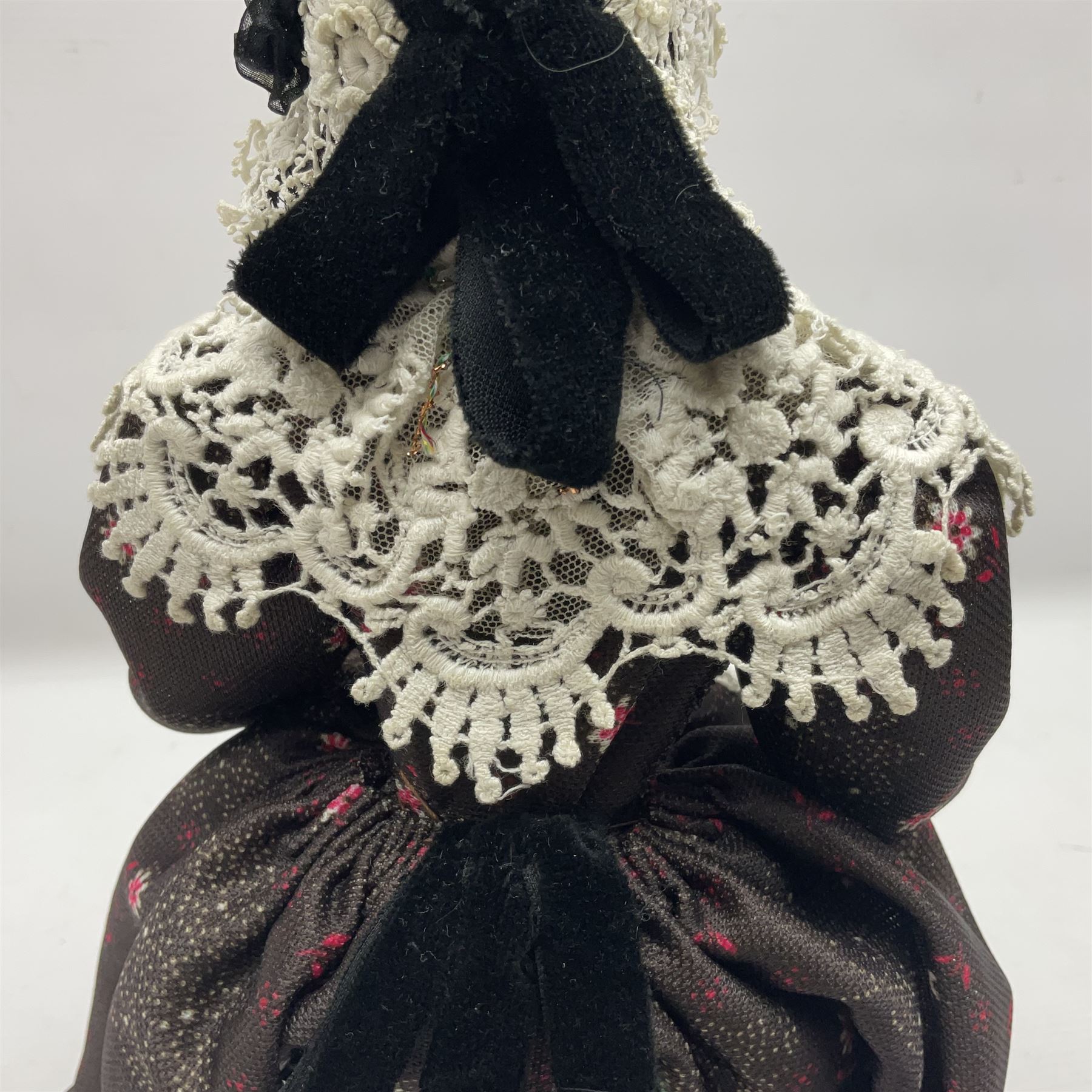 Anna Meszaros Hungary - hand made needlework figurine 'Old Lady' seated on a stool wearing a lace trimmed black/white/red floral full length dress and hat, working on a piece of lace H30cm  Auctioneer's Note: Anna Meszaros came to England from her native Hungary in 1959 to marry an English businessman she met while demonstrating her art at the 1958 Brussels Exhibition. Shortly before she left for England she was awarded the title of Folk Artist Master by the Hungarian Government. Anna was a gifted painter of mainly portraits and sculptress before starting to make her figurines which are completely hand made and unique, each with a character and expression of its own. The hands, feet and face are sculptured by layering the material and pulling the features into place with needle and thread. She died in Hull in 1998.