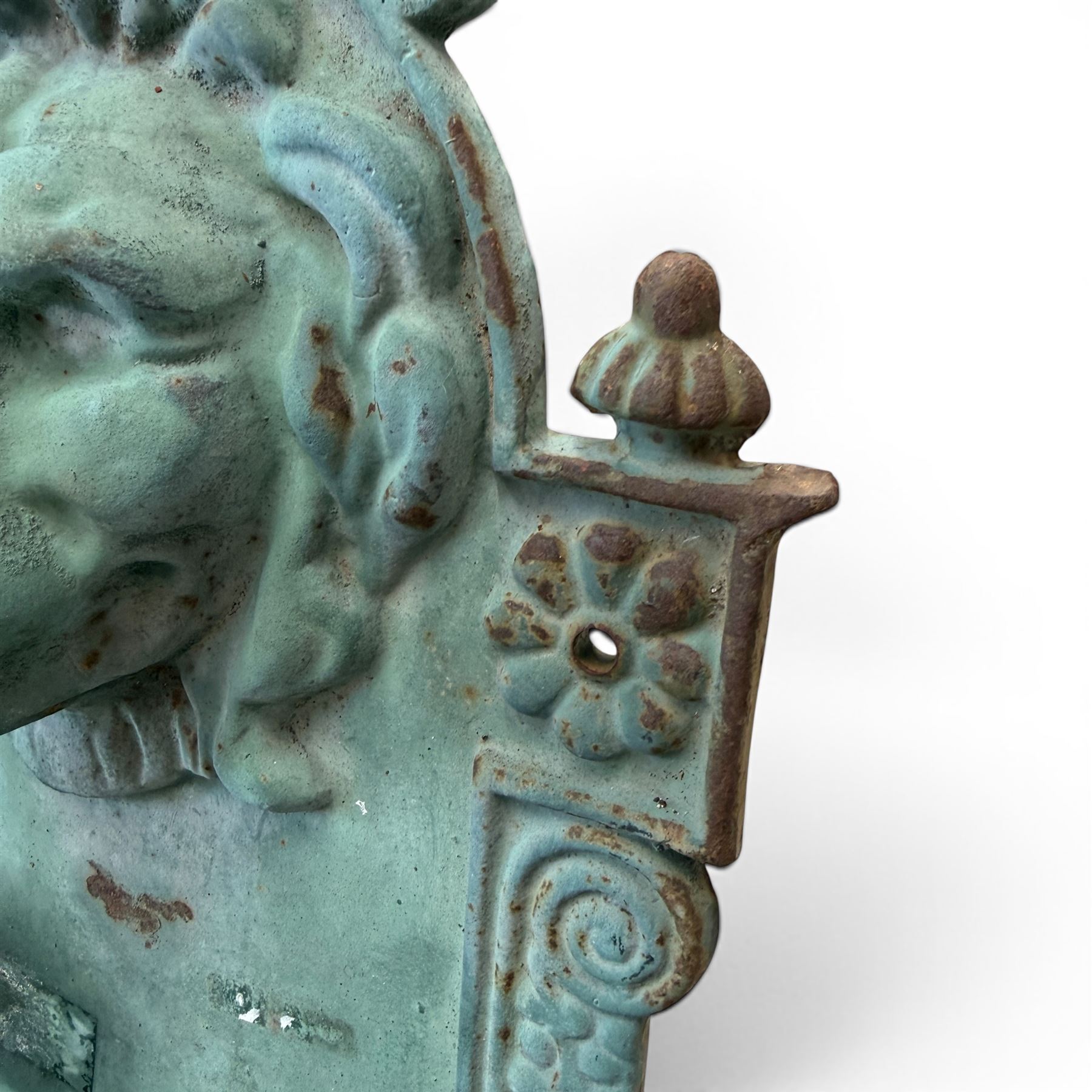Antique cast iron wall fountain, cartouche cresting rail over a lion mask spout, with scroll and floral decoration over a scalloped basin, in rustic turquoise painted finish with rusted patina