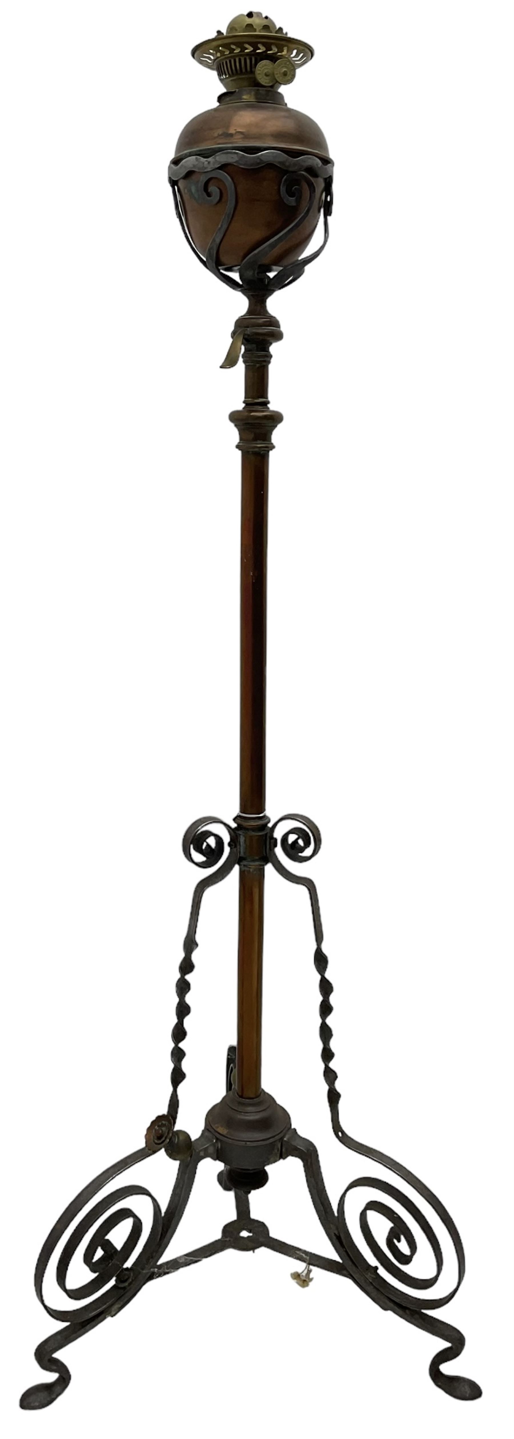 Late 19th to early 20th century wrought metal and copper telescopic oil standard lamp, the lamp and reservoir on scrolled supports with waved band, handle operating telescopic action, tripod base with scrolled terminals and twisted decoration, splayed pad feet 