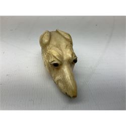 19th century carved ivory walking cane handle, modelled as the head of a greyhound with inset glass eyes, together with a further 19th century ivory example, modelled as a caricature of a gentleman's head, (2)