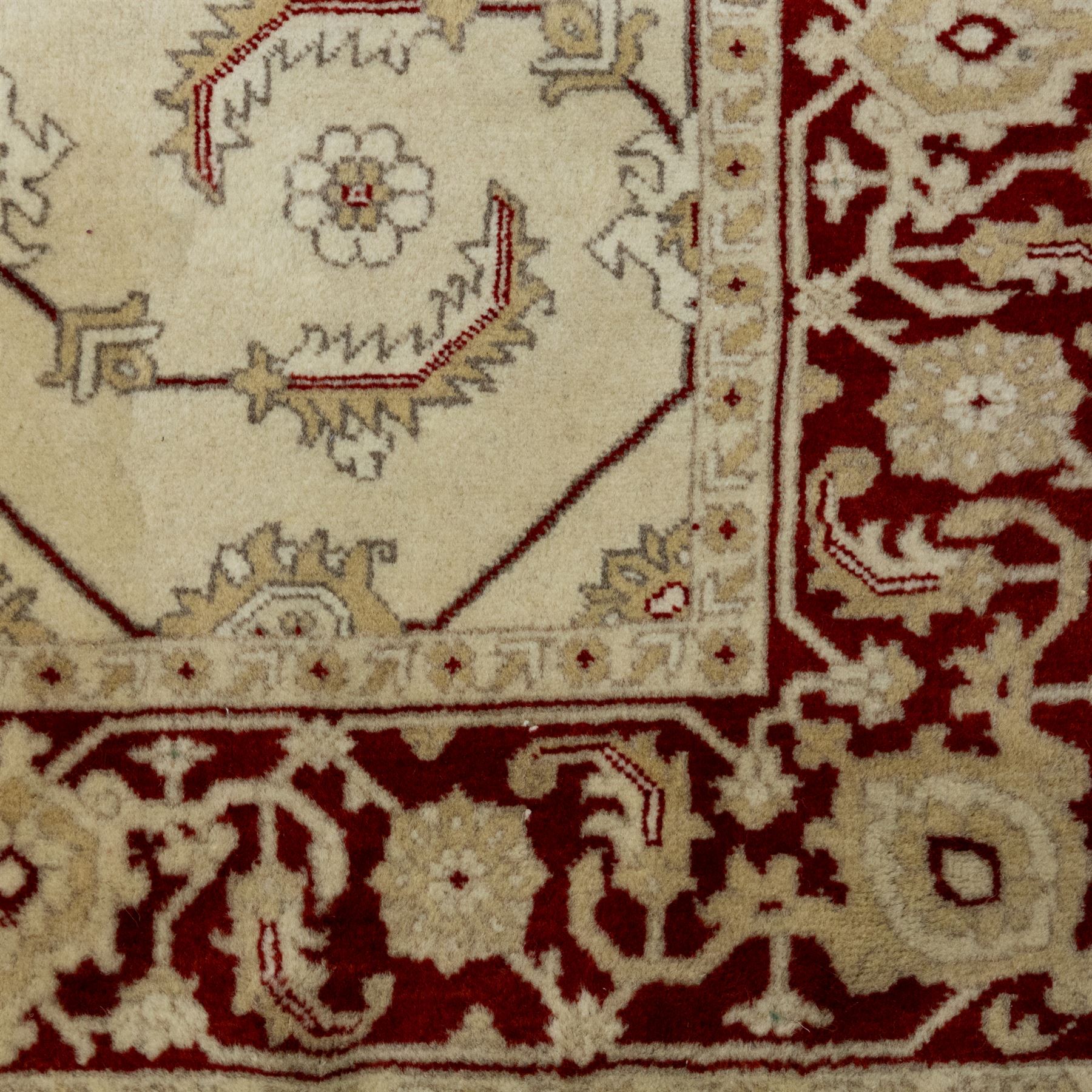 Baluchi signed hand-knotted rug, ivory ground, with an all-over geometric lattice design incorporating stylised flowerheads, hooked motifs and angular vine work, enclosed by a crimson border with repeating floral motifs and scrolling vines, flanked by narrow patterned guard stripes, signed to one corner, with cotton fringes