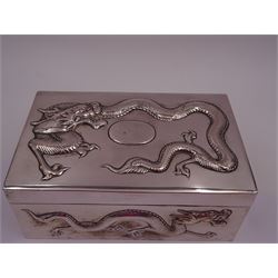 Late 19th century/early 20th century Chinese export silver mounted cigarette box, of rectangular form, decorated in relief with dragons, the hinged cover with similar dragon decoration and central blank oval cartouche, opening to reveal a softwood lined compartmentalised interior, stamped beneath with character mark and KMS for maker Kwong Man Shing, H6.3cm, W15.5cm, D9.5cm