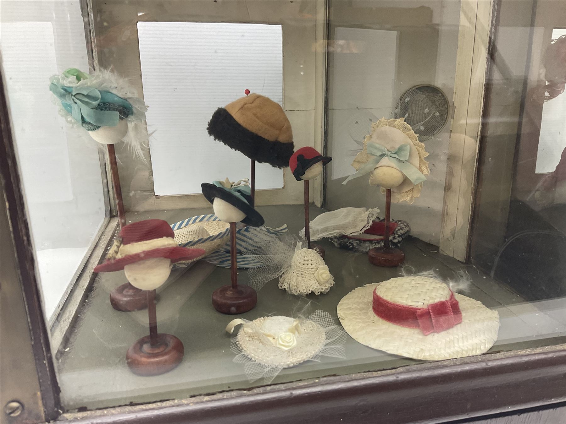 Early 20th century scratch-built wooden hat & gown shop diorama 'Joan', of double-fronted form glazed on three sides with brass and aluminium mounts, rear access apertures and storage under L63cm H45cm D31cm; with small collection of dresses and hats on display stands