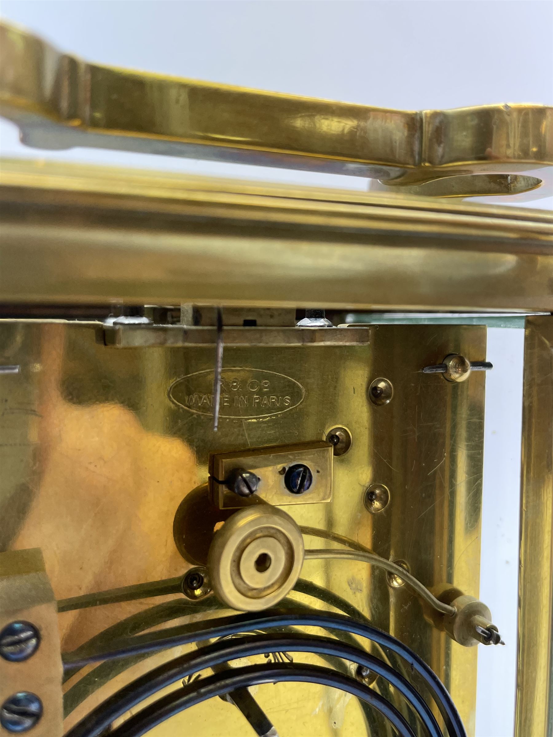 Early to mid 20th century French brass and bevelled glass cased carriage clock, the shaped loop handle over oval glass panel, white enamel Roman dial, twin train driven eight day movement striking on coil, with button push repeater, the movement back plate stamped for 'R & Co.'