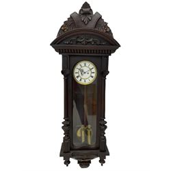 A late 19th century German Vienna style weight driven wall clock c1880, with a predominant arched pediment and applied carving, case with glass side panels (one missing) and a glazed full-length arched door flanked by reeded columns with decorative capitals, 7' two-piece white enamel dial with roman numerals, minute markers and pierced steel gothic hands, pendulum with a wooden rod, pressed brass bob and beat plate, eight-day weight driven movement striking the hours and half hours on a coiled gong. With brass cased weights.



