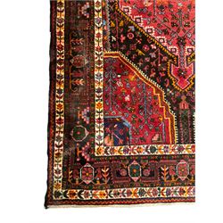 Persian Hamadan red and blue ground rug, the field with extending lozenge decorated with small stylised flower head motifs, the spandrels decorated with tree of life motifs, within a multi-band border with overall geometric design