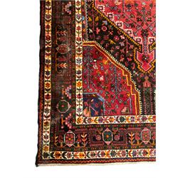 Persian Hamadan red and blue ground rug, the field with extending lozenge decorated with small stylised flower head motifs, the spandrels decorated with tree of life motifs, within a multi-band border with overall geometric design