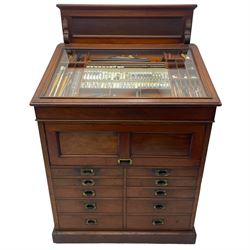 Edwardian mahogany artist's cabinet once belonging to the British artist Eli Marsden Wilson (1877-1965), raised panelled back mounted by carved brackets, sloped and hinged glazed lid enclosing paint holders and compartments, up-and-over panelled door revealing three slides, fitted with two banks of five graduating drawers with recessed brass handles, on skirted base.

Together with a quantity of artists' equipment and tools including paints, paintbrushes, charcoal, chalks, etc. and various prints relating to the life of the artist, including Quaker anti-war posters, Victorian Stevengraphs, and various chromolithographs 

Provenance: Removed from the studio of Eli Marsden Wilson. The cabinet comes to us for sale through family descent. The vendor is descendant of Marsden. Many further etchings removed from the cabinet are being sold in the Spring Art Sale, Friday 15th March 2024, Lots 265-271.

Notes: born in Ossett, Eli Marsden Wilson was the only son of Alfred Wilson, a foreman beamer, and Emma Marsden, and had five sisters. After studying at Wakefield College of Art, he moved to the Royal College of Art in London, where he became a pupil of Sir Frank Short. He had his first exhibit at the Royal Academy in 1905, the same year he married fellow artist Hilda Mary Pemberton.

A Quaker, vegetarian, and pacifist, he was a conscientious objector in World War I and as such was imprisoned in 1917 for two years. In September 1922 he was commissioned by Princess Marie Louise to produce miniature etchings for Queen Mary's Dolls' House at Windsor Castle; two such etchings are being sold in the Spring Art Sale, Friday 15th March 2024, Lot 265.