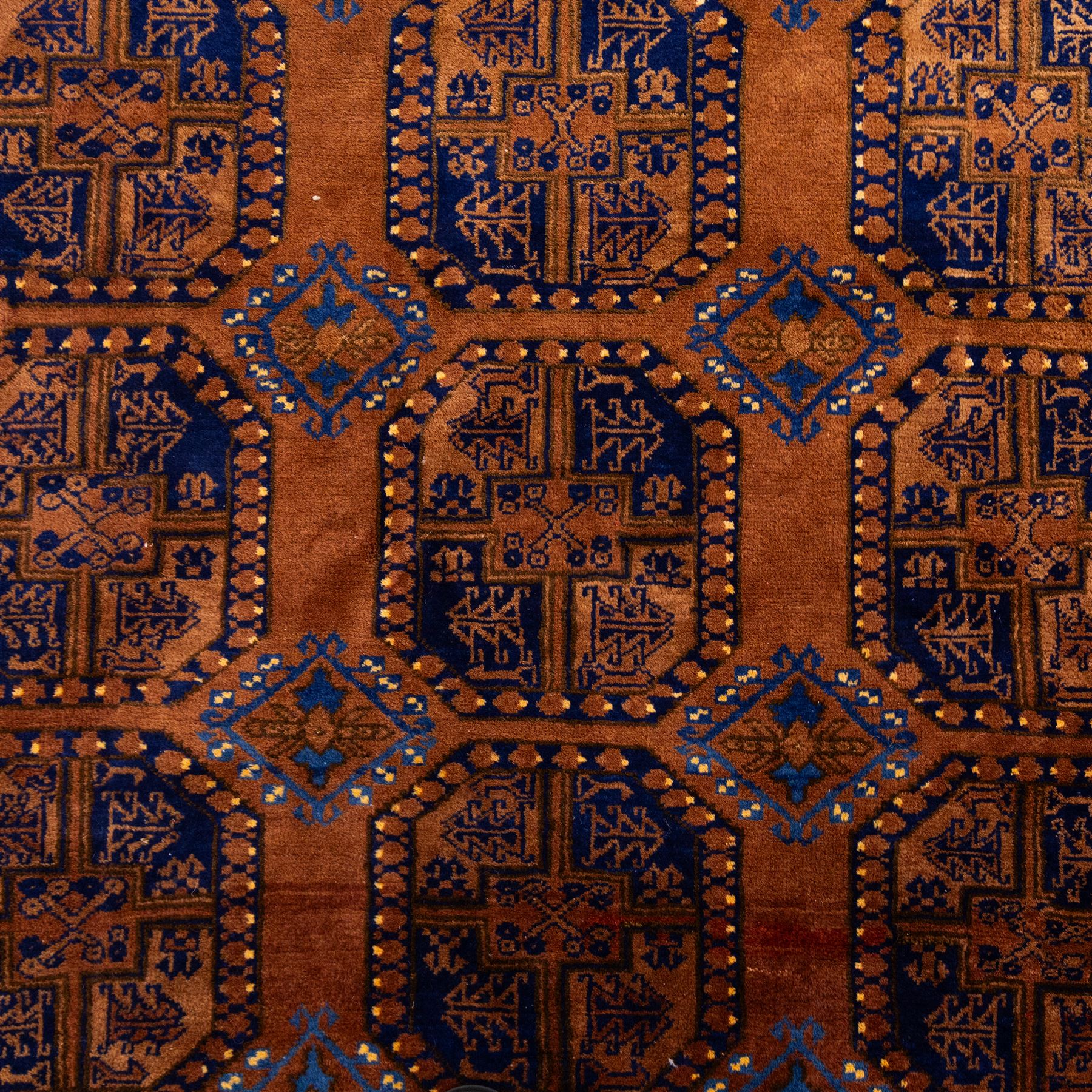 Pakistani Bokhara hand-knotted carpet, camel field decorated with rows of large tekke style octagonal guls enclosing stylized geometric motifs, interspersed with small stepped diamond devices within multiple geometric borders, with fringe ends 